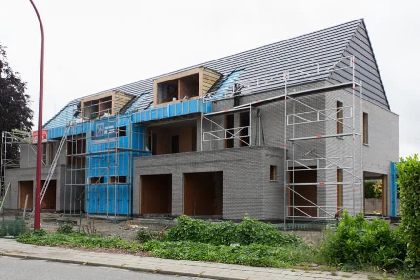 Woning in aanbouw in Waarloos, Kerkelei met steigers en blauwe dakbeschermfolie tijdens de werken door Dakwerken De Haes.