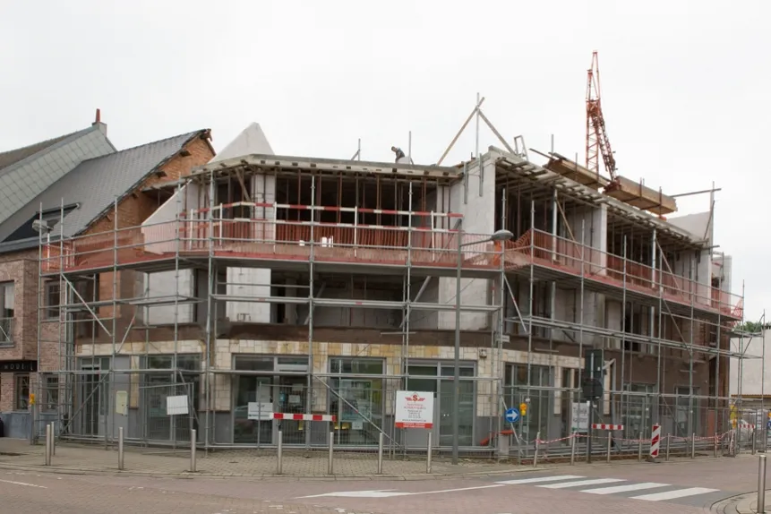 Commercieel gebouw in aanbouw in Sint-Katelijne-Waver, Dorp, met steigers en kraan tijdens de plaatsing van gevelbekleding door Dakwerken De Haes.