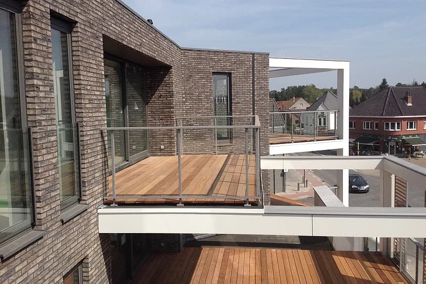 Moderne dakwoning in Tremelo met houten terras en glazen balustrade, timmerwerk uitgevoerd door Dakwerken De Haes.