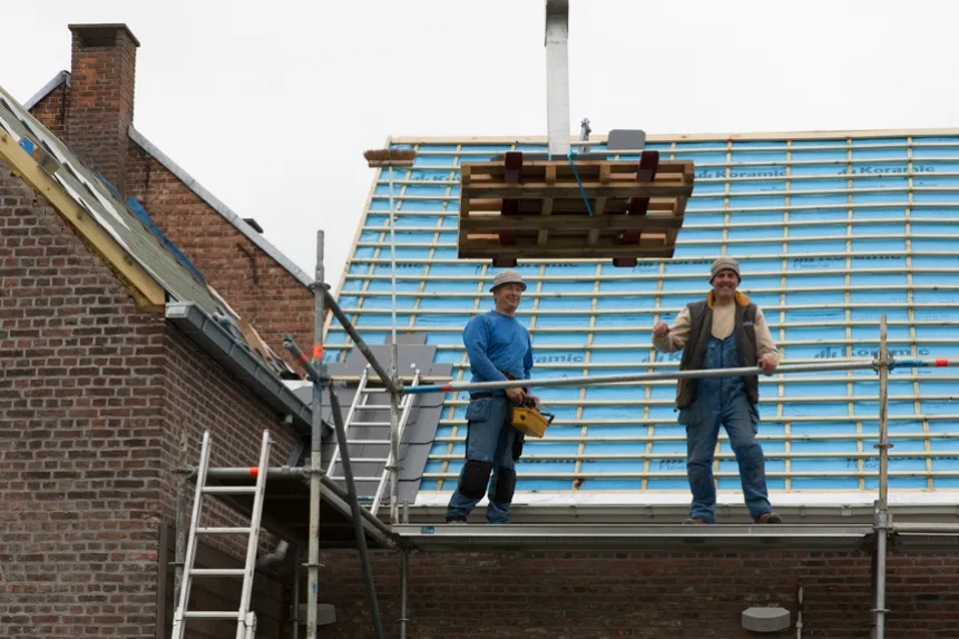 Twee dakwerkers van Dakwerken De Haes op het dak in Onze-Lieve-Vrouw-Waver, Heiken tijdens de plaatsing van isolatie en daklatten.