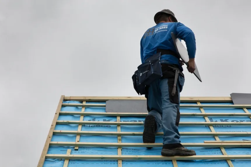 Dakwerker van Dakwerken De Haes loopt op het dakgeraamte met isolatiefolie tijdens de renovatie in Onze-Lieve-Vrouw-Waver, Heiken.