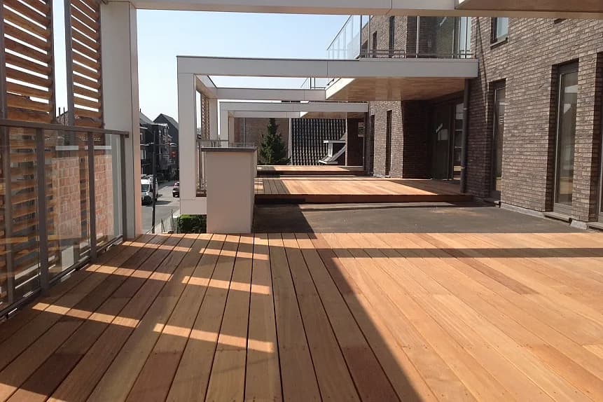 Overzicht van de houten terrasdekken en witte pergola-structuur op het project Pharma Finance in Tremelo, door Dakwerken De Haes.