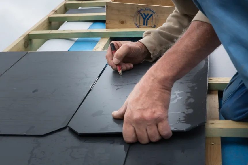 Dakwerker van Dakwerken De Haes meet en markeert leistenen dakpannen nauwkeurig tijdens de plaatsing in Onze-Lieve-Vrouw-Waver, Heiken.
