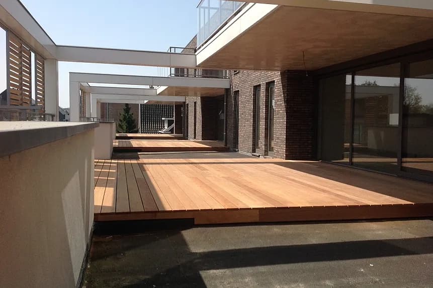 Doorzicht over de houten terrassen en pergola's van het commercieel project Pharma Finance in Tremelo, uitgevoerd door Dakwerken De Haes.